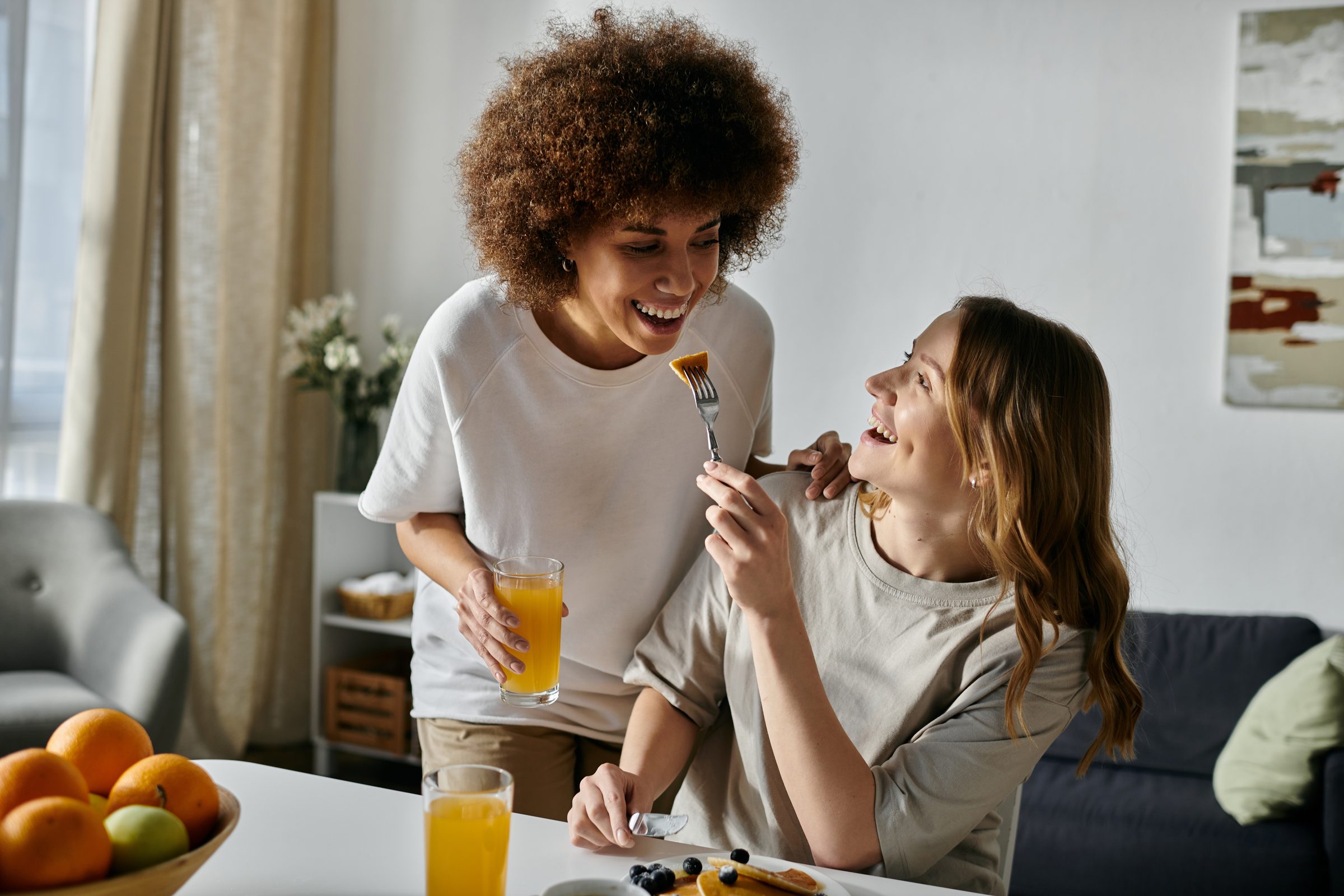 Two women laugh together over breakfast at home
