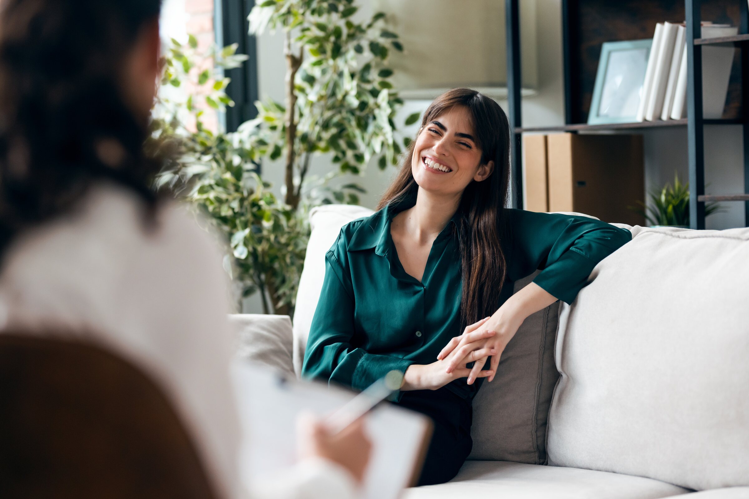A woman smiles and relaxes on a couch during a therapy session