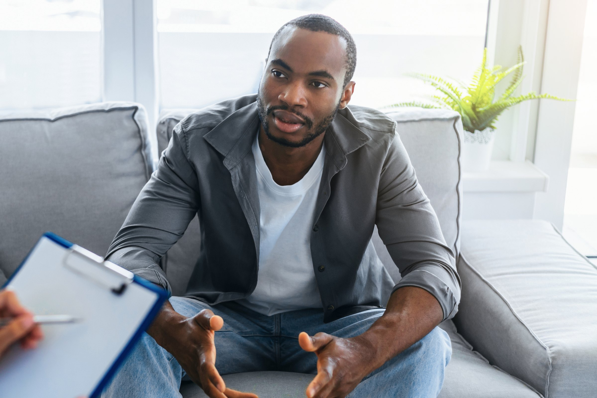 A man on a couch talking with his therapist during a session.